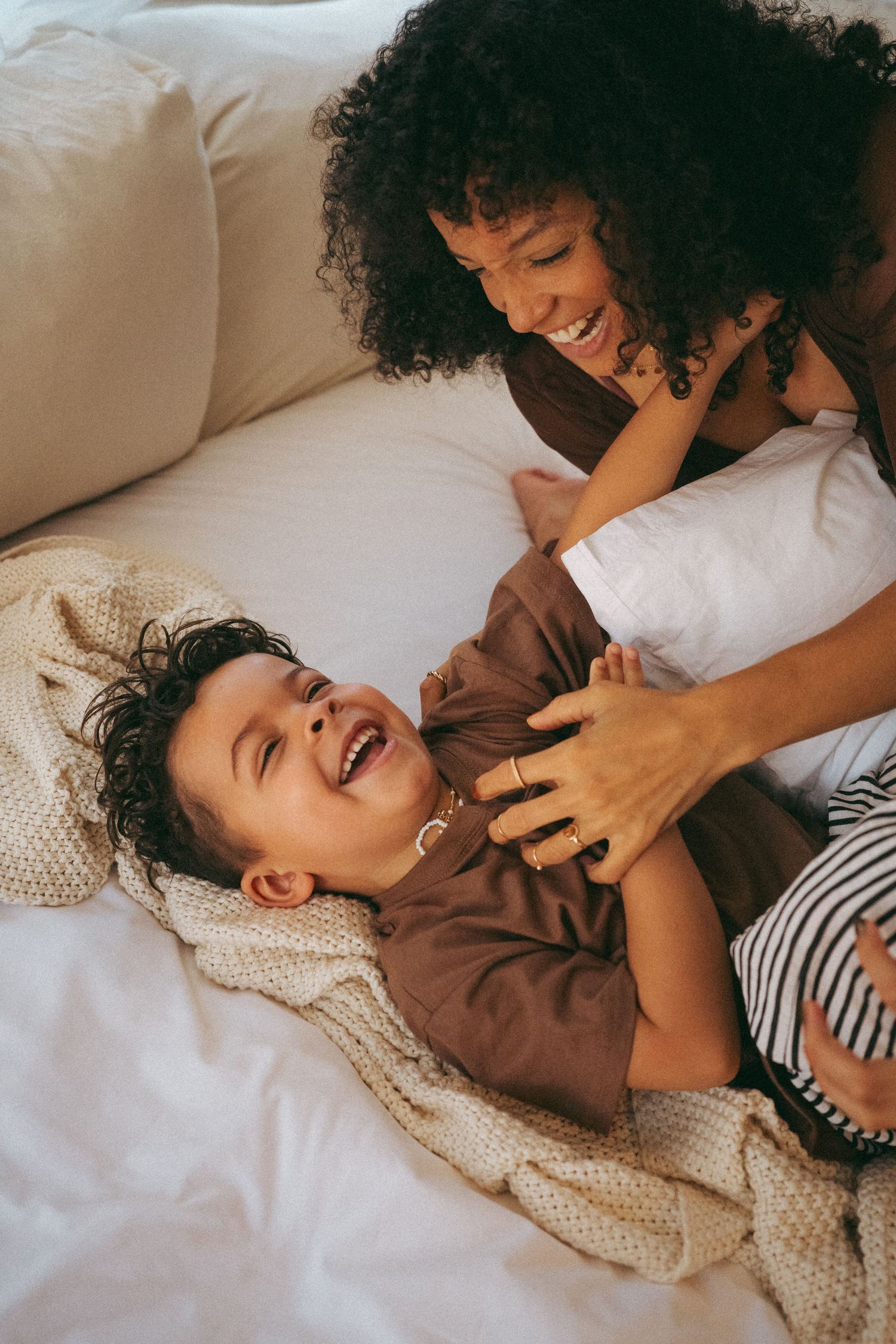Candid moments of playful interaction on white bedding.