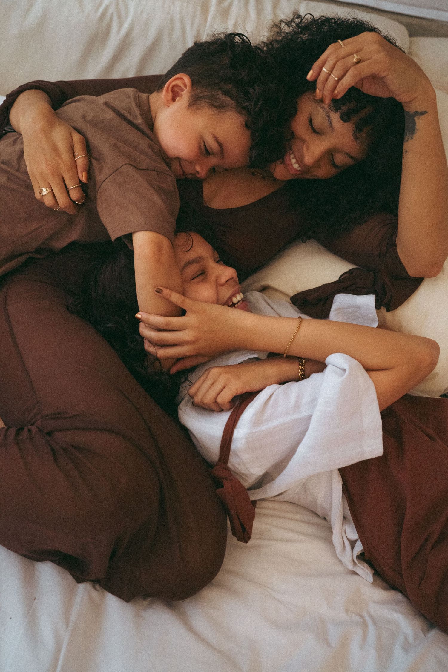 Candid lifestyle photos showing warm embraces between parent and child on white sheets.