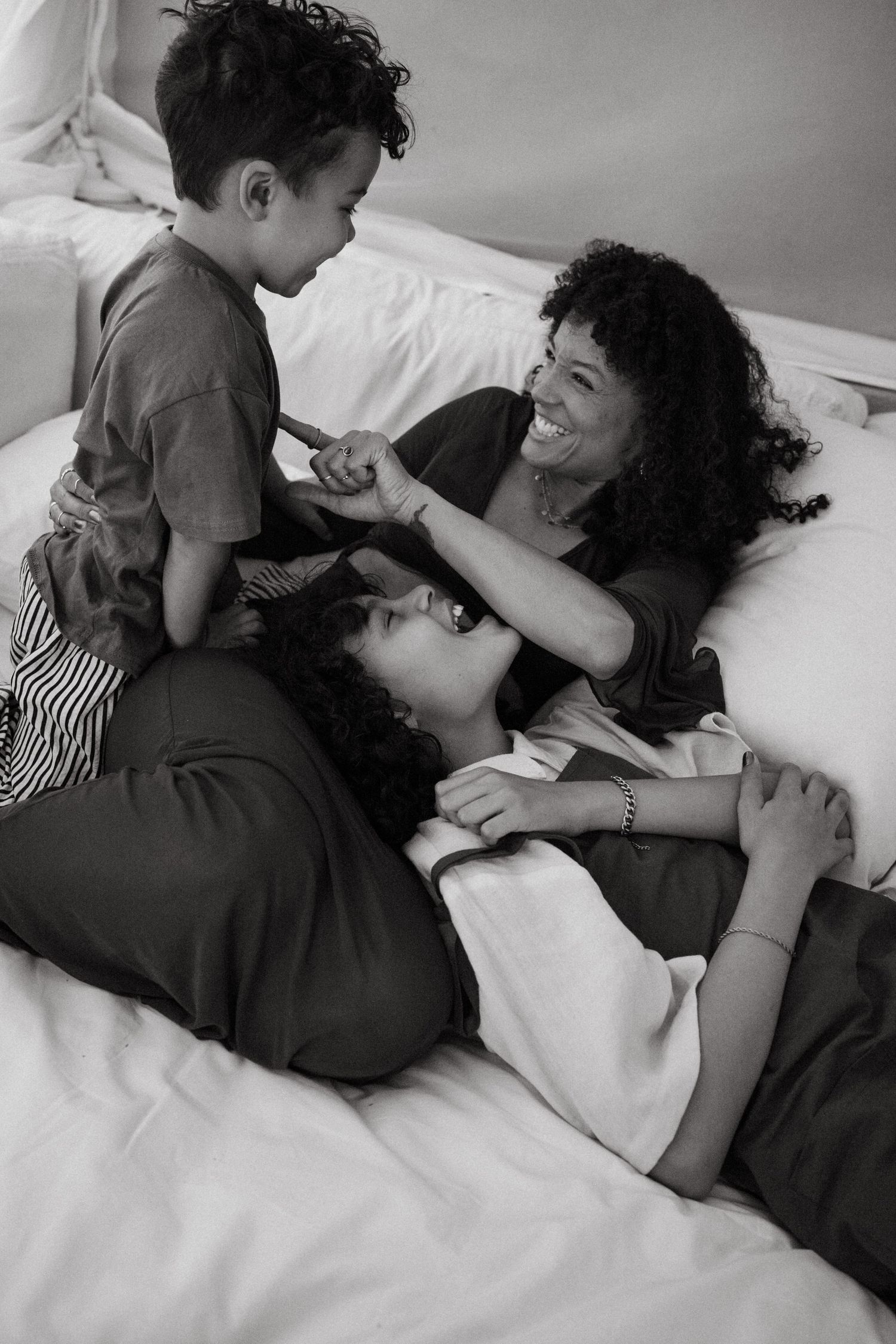 Sweet candid moments between parent and child playing together on white bedding.