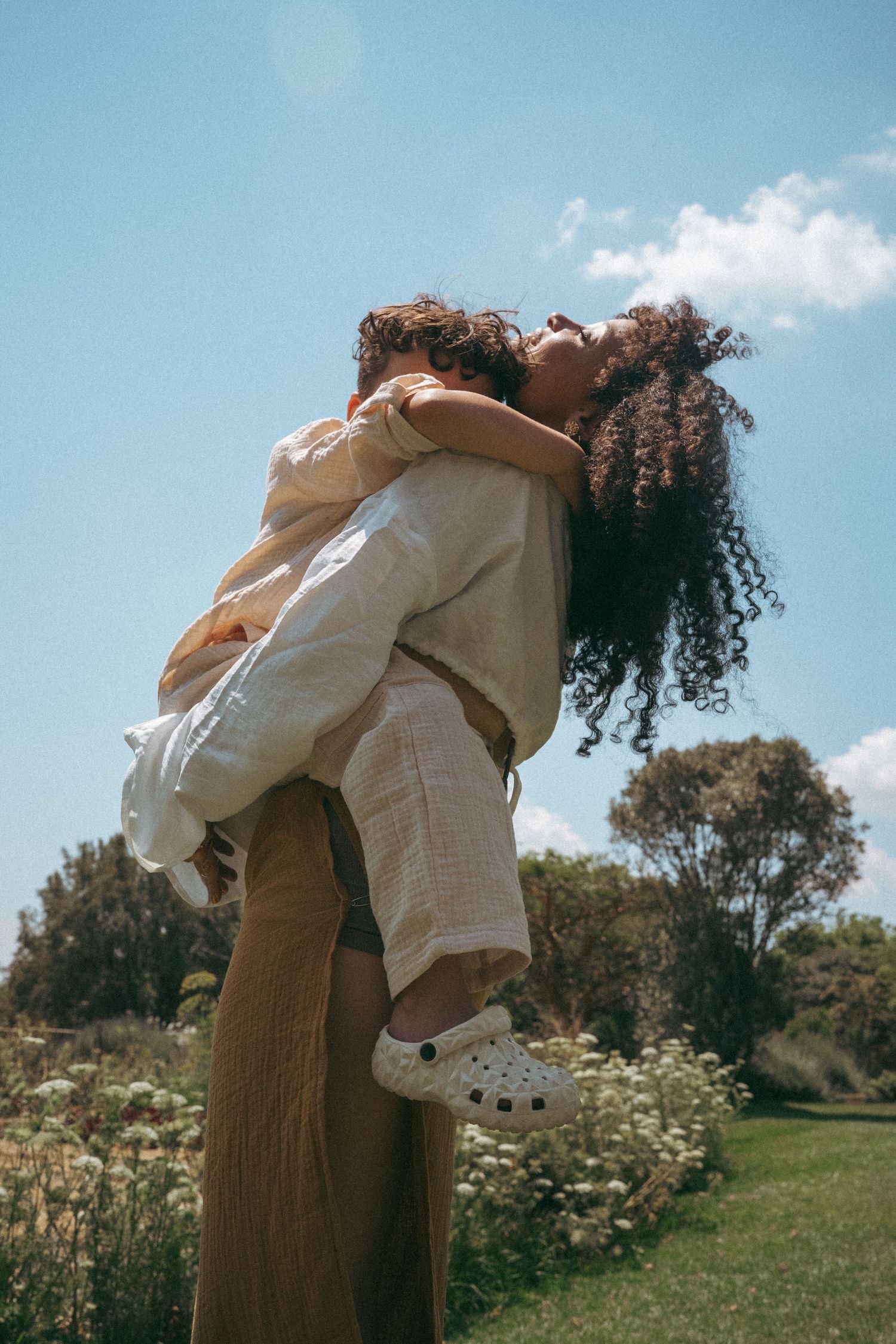 Tender moment photographed in a meadow with white and brown clothing.