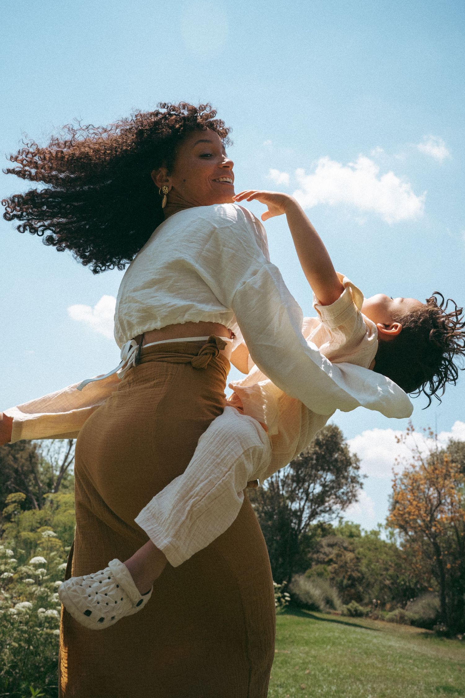 Dynamic movement captured in sunlit field wearing white top and brown bottoms.