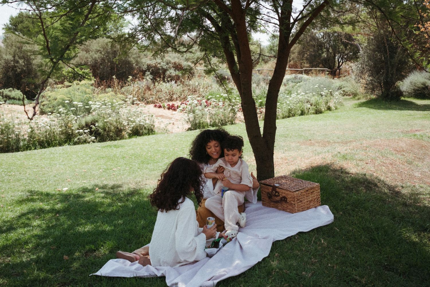 Candid moments captured in a sunlit garden with white clothing and natural surroundings.