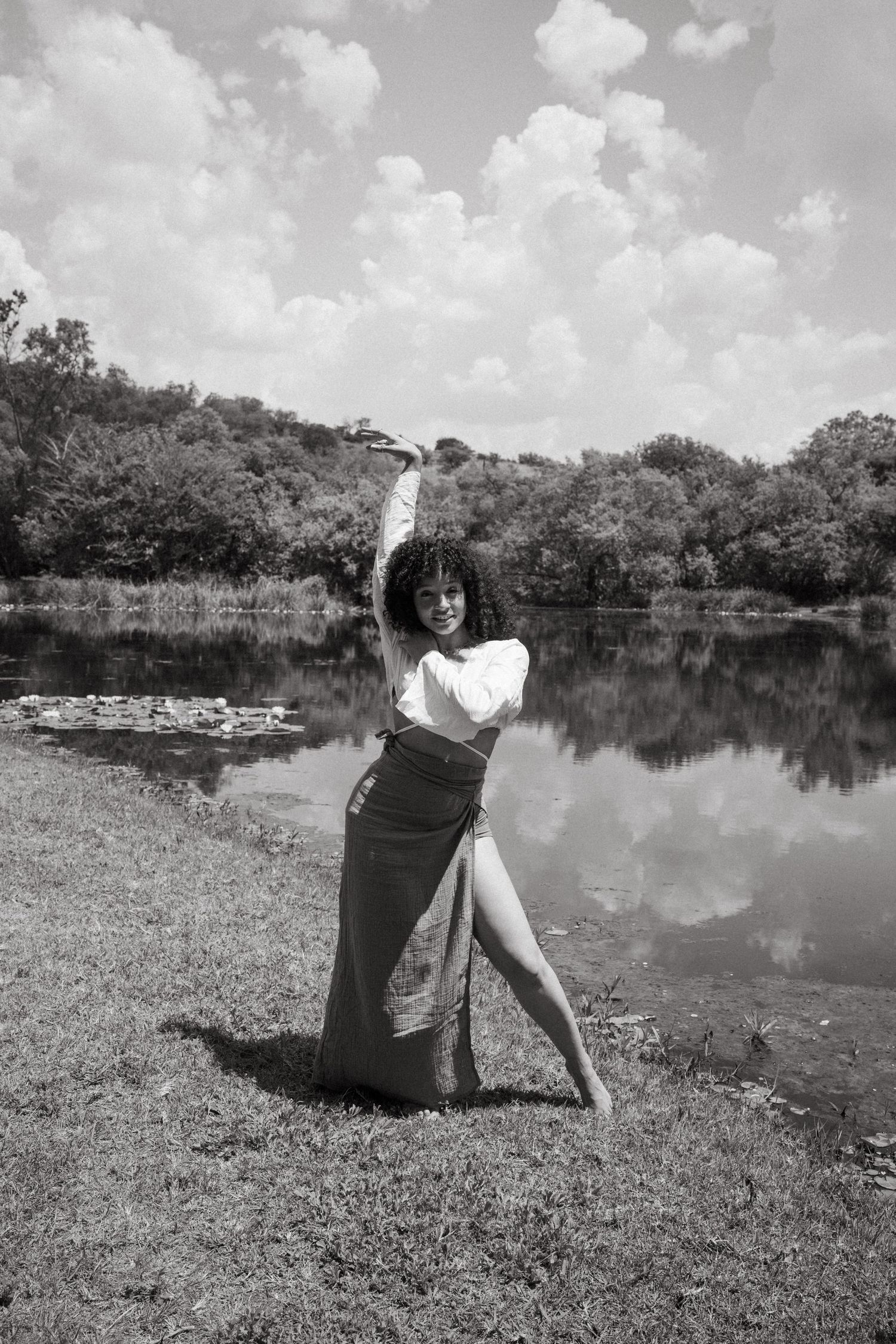 Black and white series showing playful poses by a serene lake with floating lily pads.