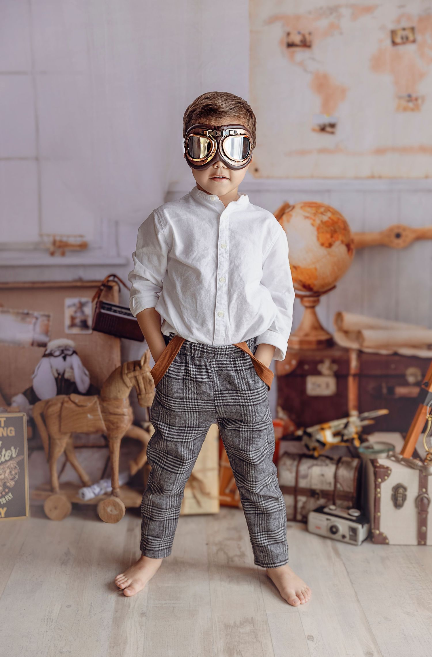 Fotografio a nino con gafas estilo steampunk tiene sus manos en el bolsillo en un escenario de exploradores antiguo.