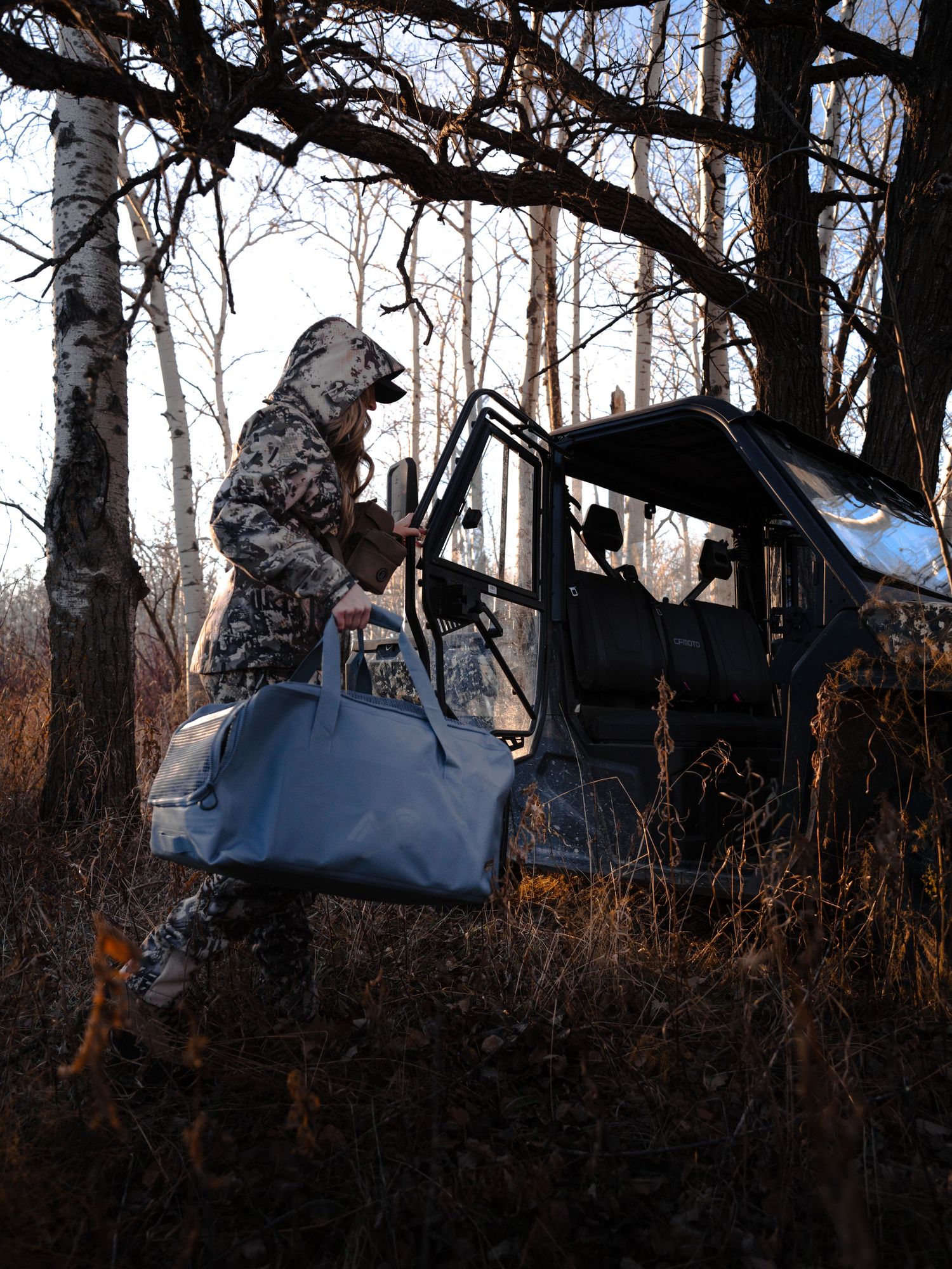 Outdoor gear and equipment arranged against natural wooded backdrop at sunset.