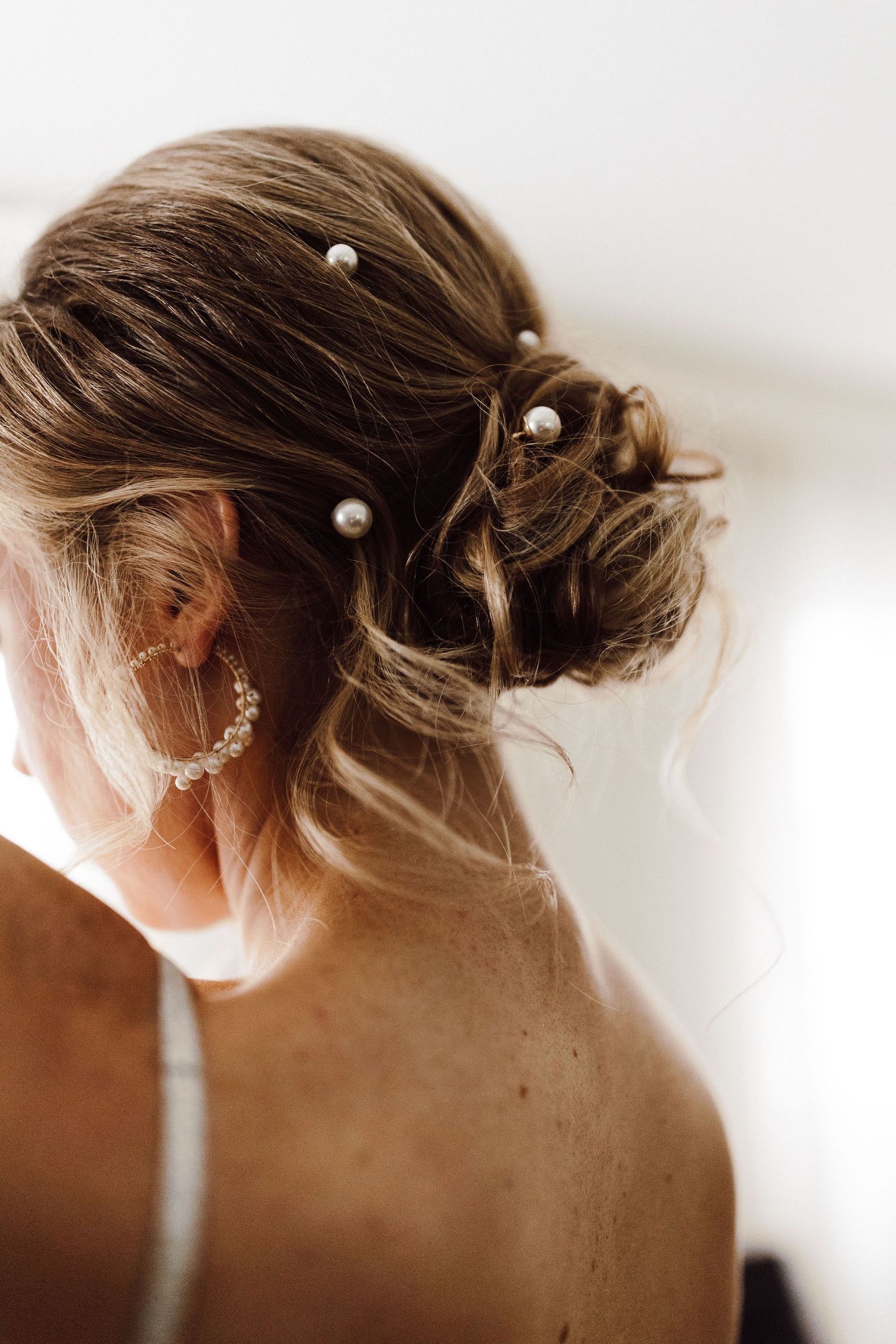 Close-up view of an elegant bridal updo hairstyle with delicate pearl pins and soft waves.