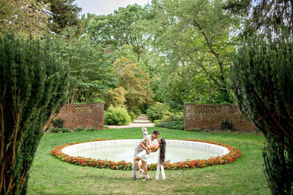 A panoramic view of a beautiful garden setting with a circular pool and lush greenery.