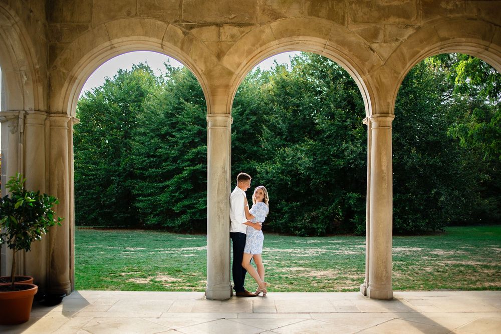 A panoramic view of stone arches overlooking a lush green garden with trees and potted plants.