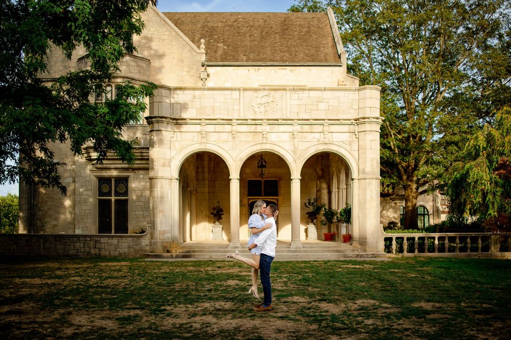 A classic stone building with arched columns and a person standing in front on a sunny day.