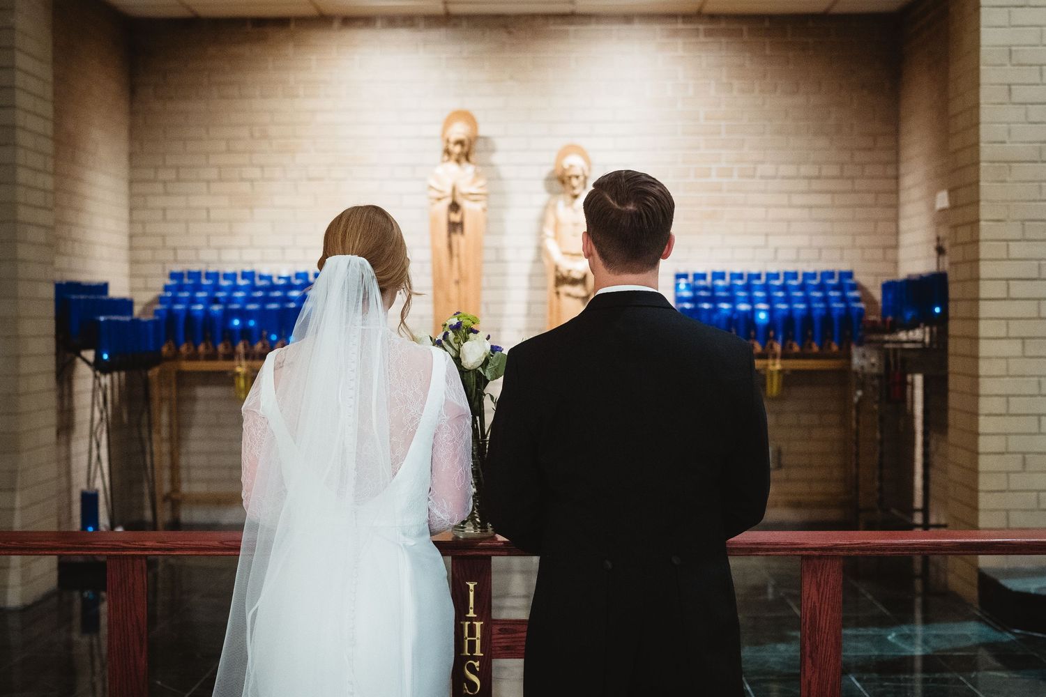 A couple in formal wedding attire stands at the altar during their church ceremony.