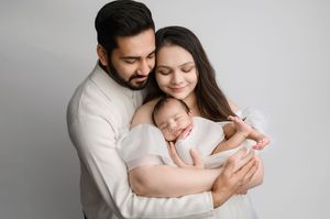 A series of intimate black and white photographs showing tender family moments in a minimalist studio setting.