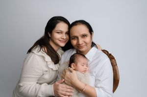 A family portrait series showing intimate moments between parents and their newborn baby against a light gray backdrop.