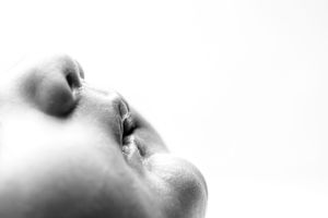Black and white close-up profile portrait showing facial features in soft focus against white background.