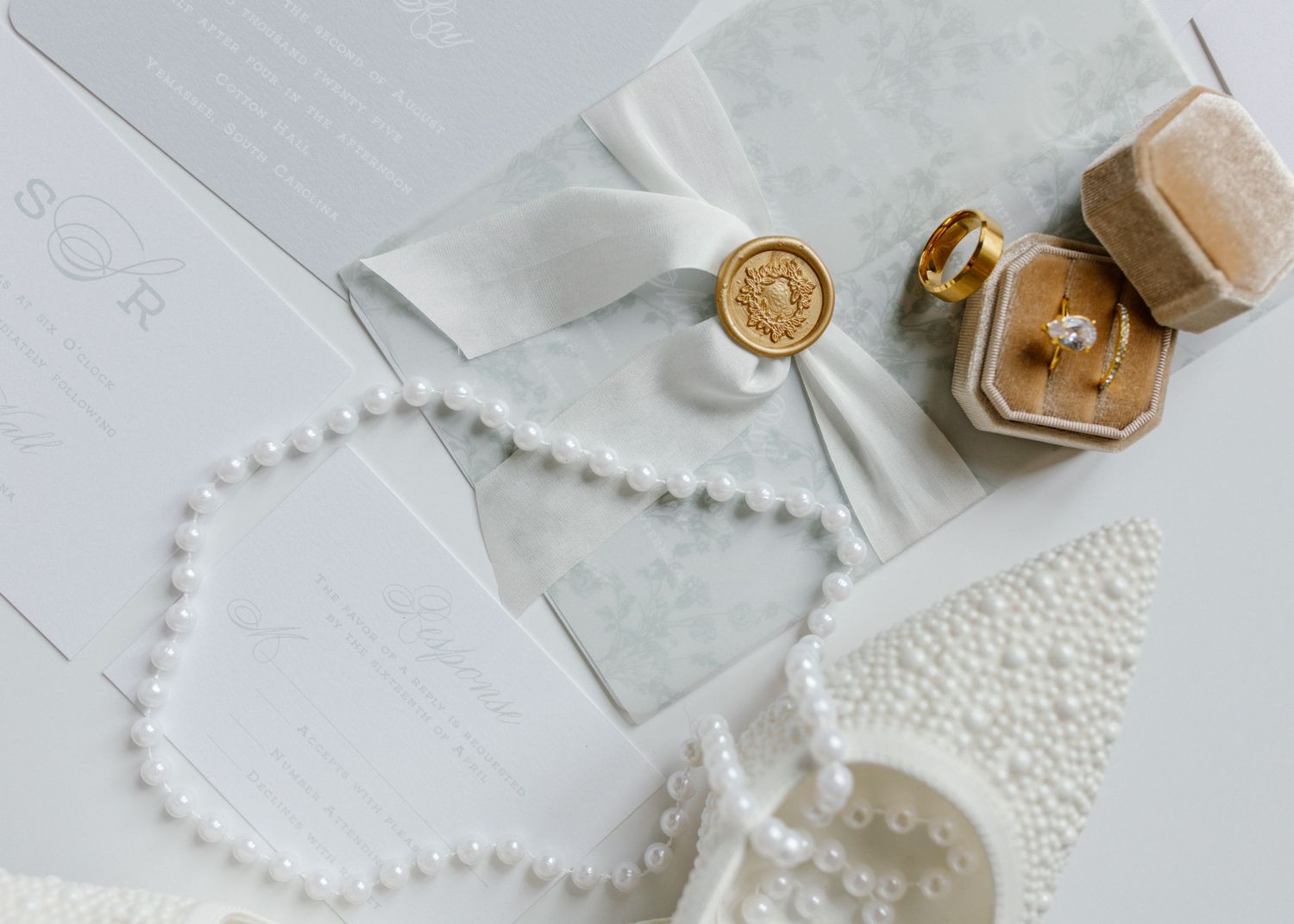 Pearl necklaces and delicate wedding accessories arranged on a light gray surface.