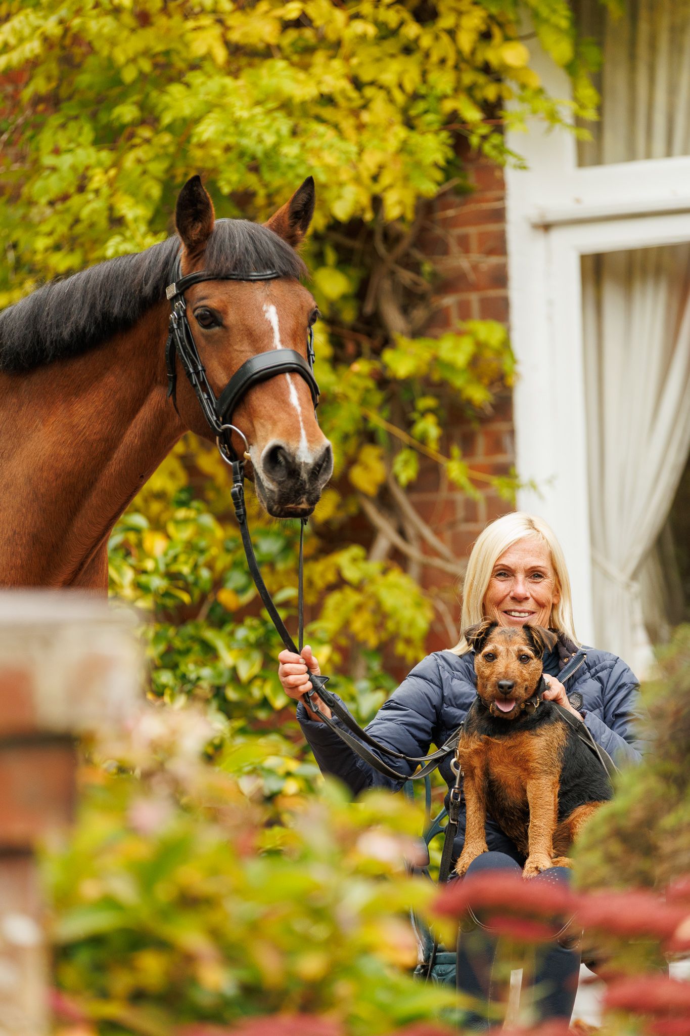 A group poses with horses along a tree-lined path during a sunny autumn day for outdoor photos.
