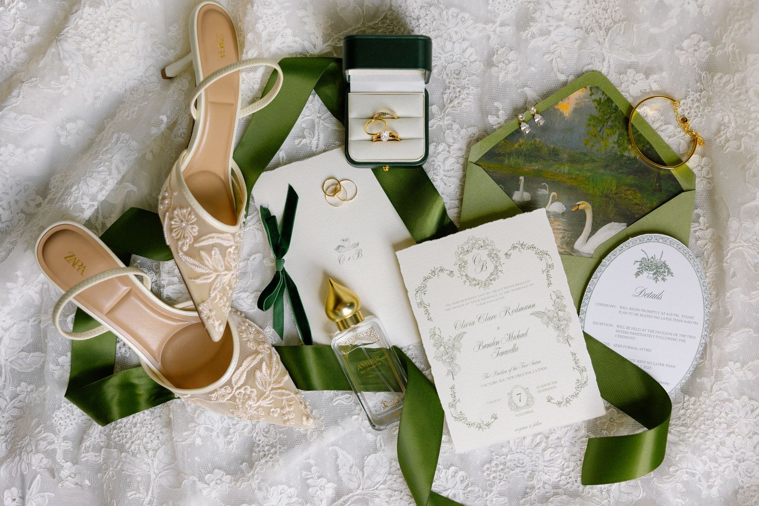 Elegant beige wedding heels arranged with green foliage and white invitation cards on a textured surface.