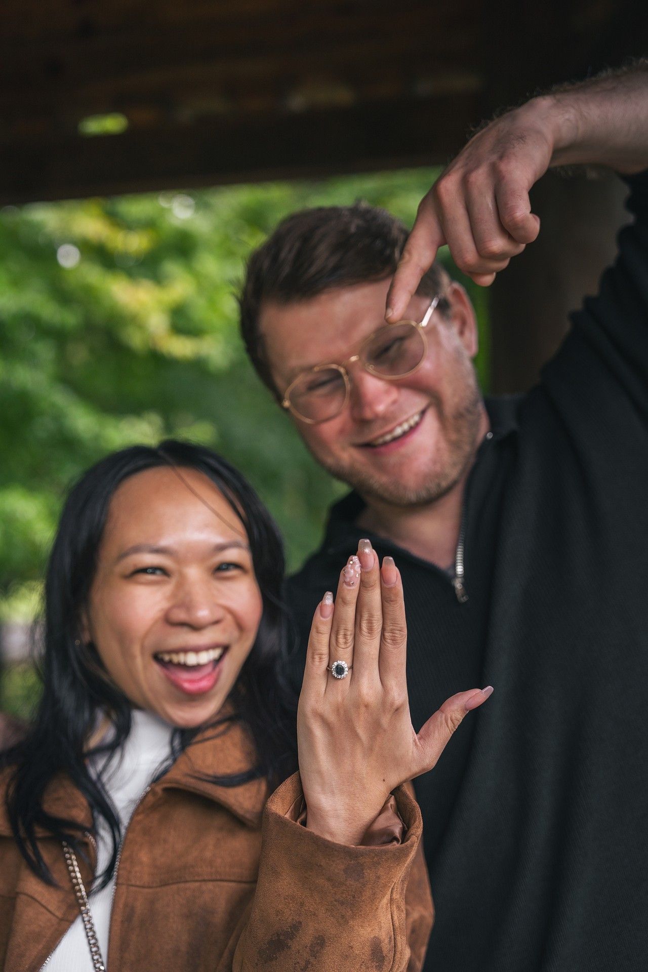 A couple shares joyful moments during their outdoor engagement photo session in a natural setting.