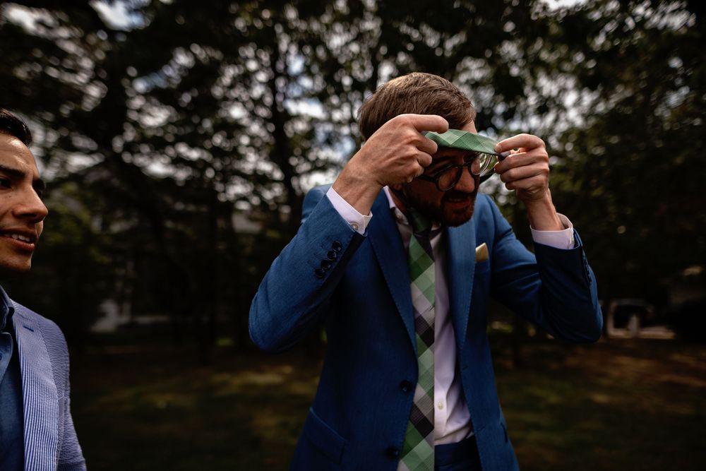A couple in formal wedding attire embraces during their first dance at an outdoor reception under trees at dusk.