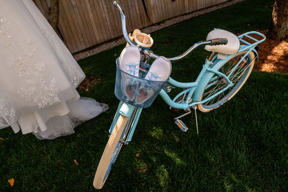 A vintage turquoise bicycle decorated with white flowers serves as a romantic wedding decor piece on a lawn.