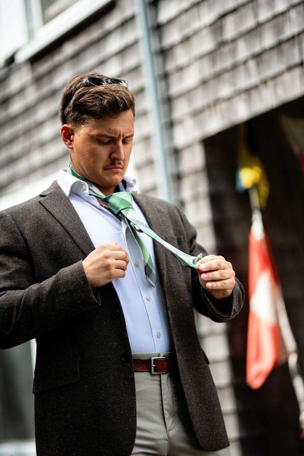 A person in a dark suit and white shirt adjusts their green tie in a sequence of photos.