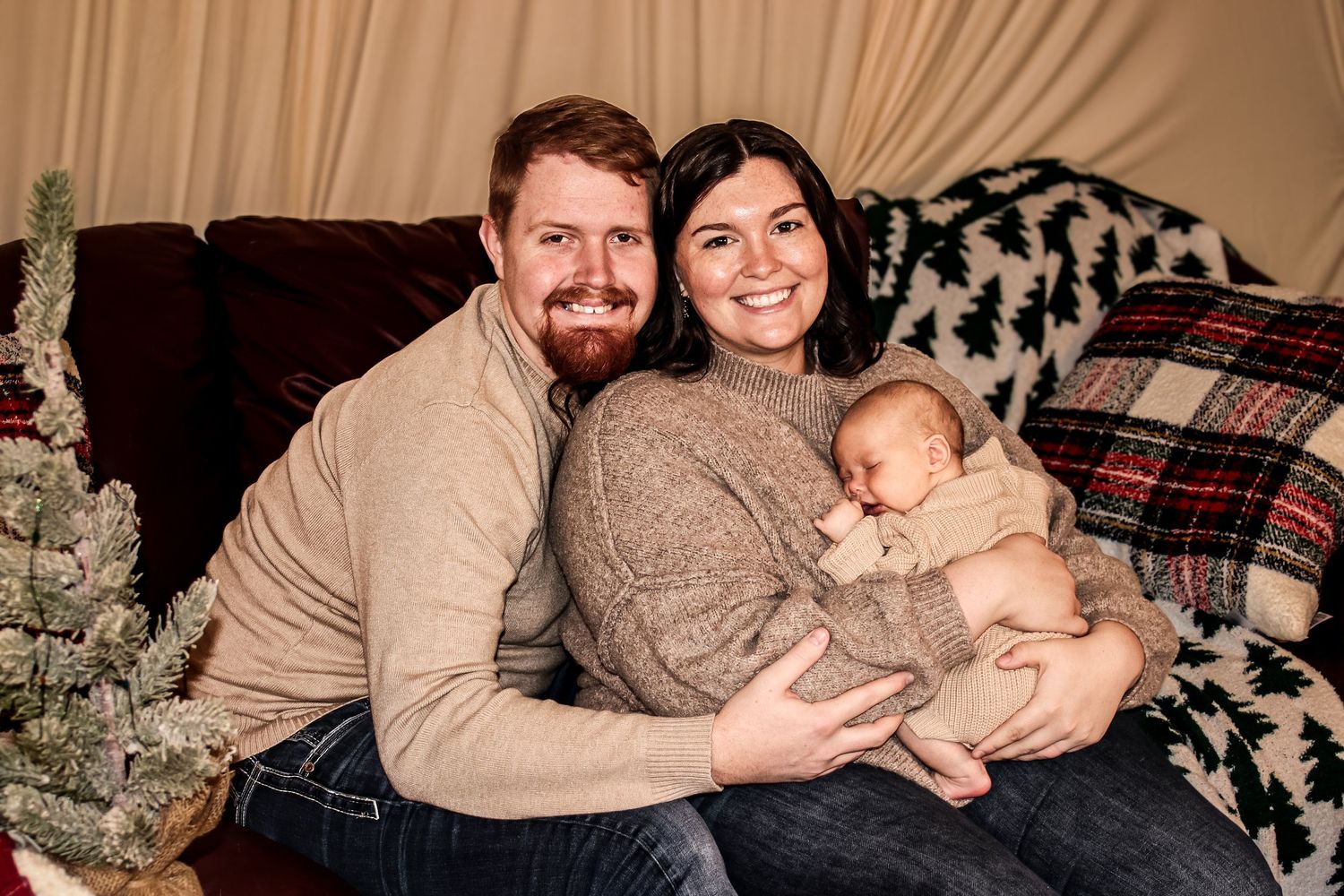 Intimate family, portrait of parents holding their newborn on a couch during an in-home lifestyle session in Michigan