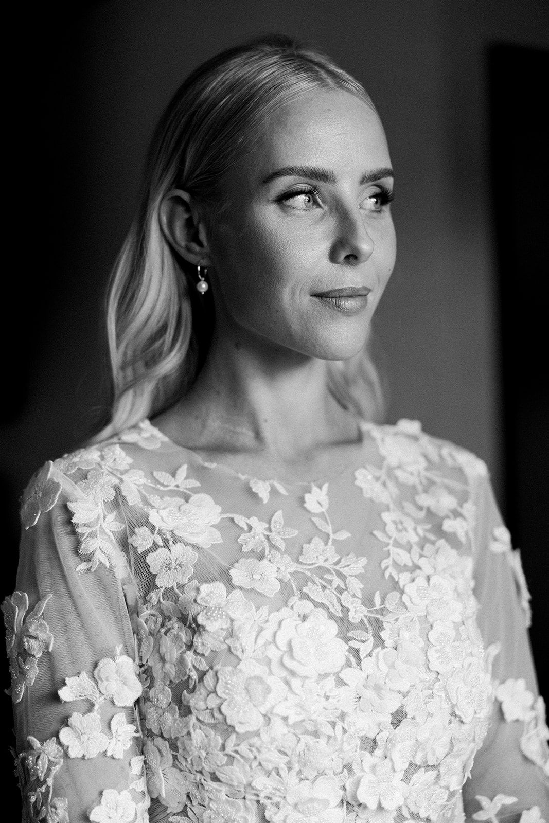 Delicate white lace floral appliques adorn sheer fabric on a wedding dress sleeve.