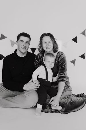 Family lying together on white floor with triangle banner decorations.