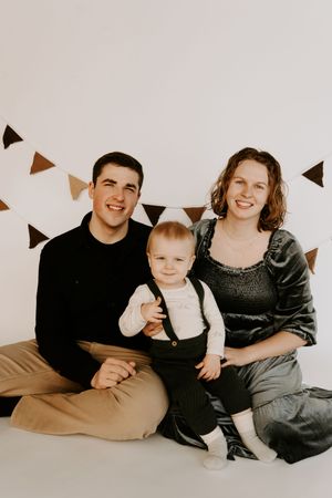 Casual family portrait session with brown and grey tones against white background.
