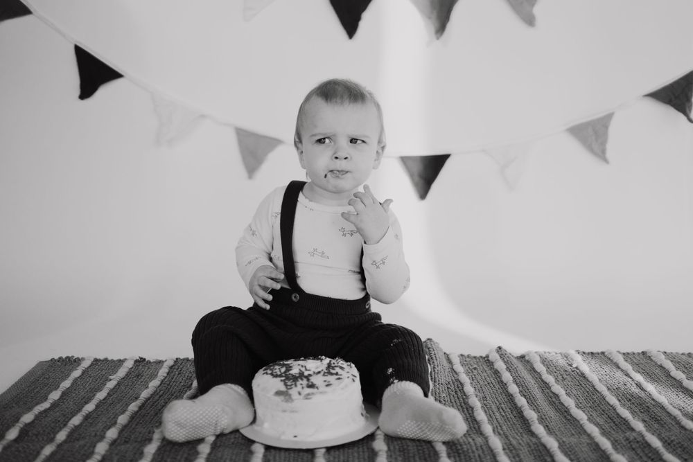 Black and white photo of a birthday celebration with cake and bunting decorations.