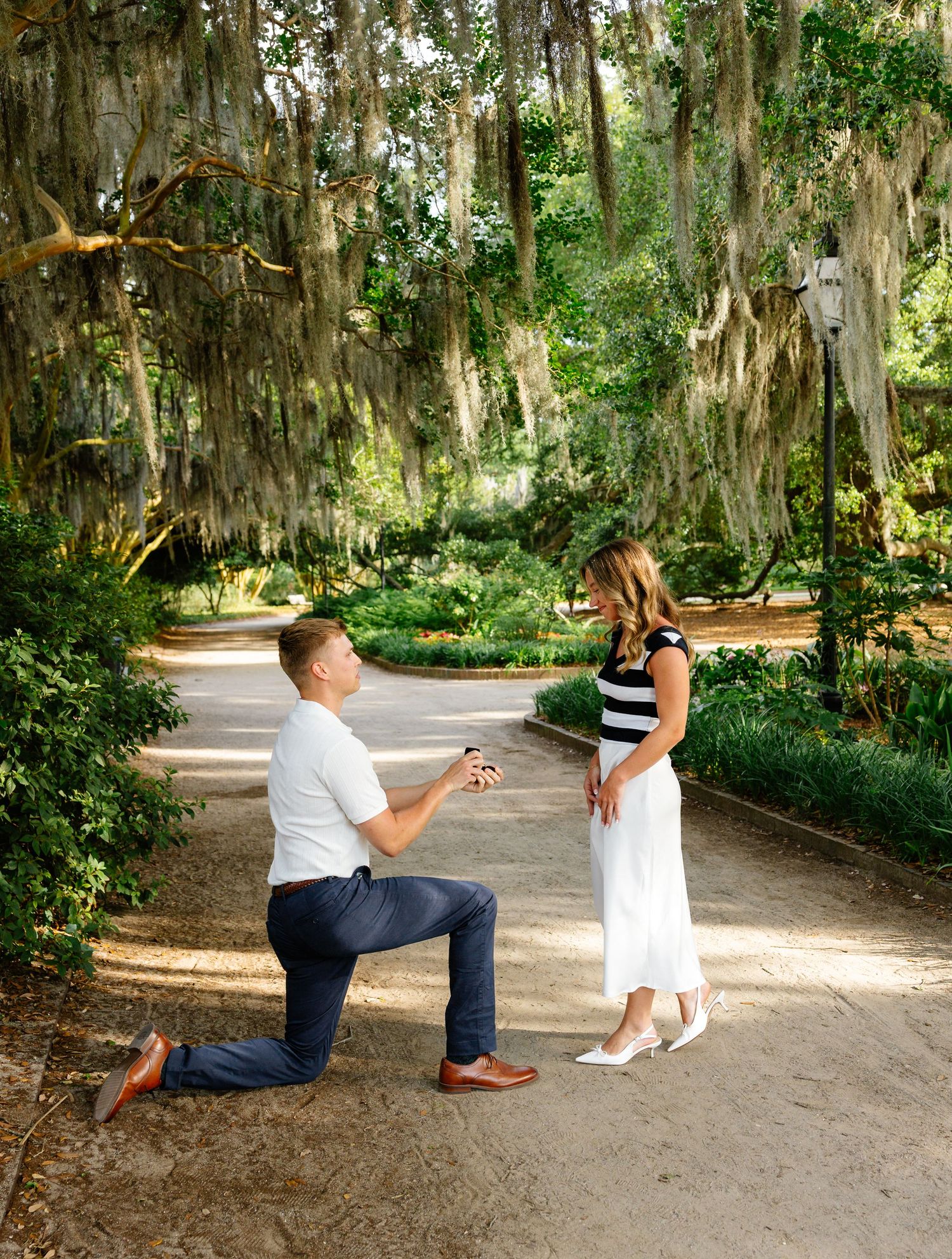 Surprise proposal moment captured at a white farmhouse with picturesque white fence.