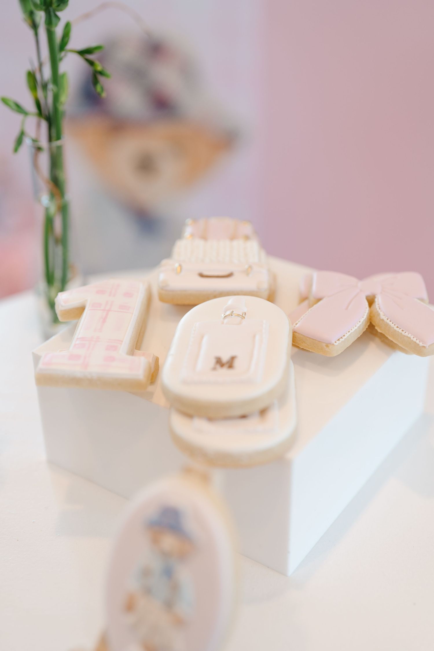 Custom pink and white iced sugar cookies spelling one for a baby's first birthday celebration.