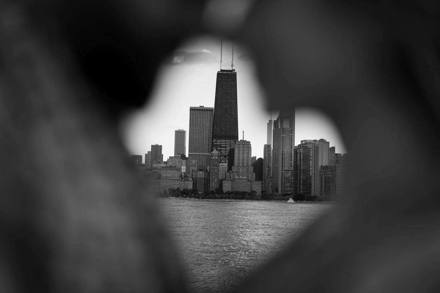 Black and white photo of Chicago skyline with John Hancock Center framed through a heart-shaped opening.