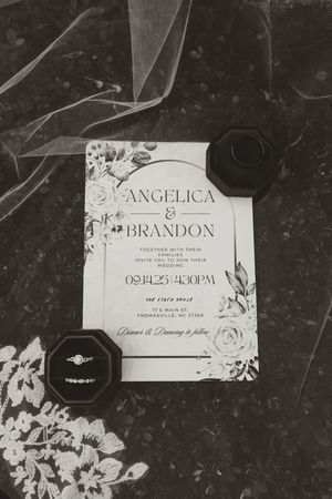 Black and white photo of Angelica and Brandon wedding invitation with ring box.