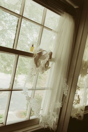 Lace-trimmed bridal veil draped over a sunlit window with soft natural light.