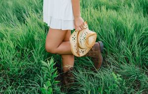Brown leather boots stand in lush green grass creating a rustic outdoor scene.