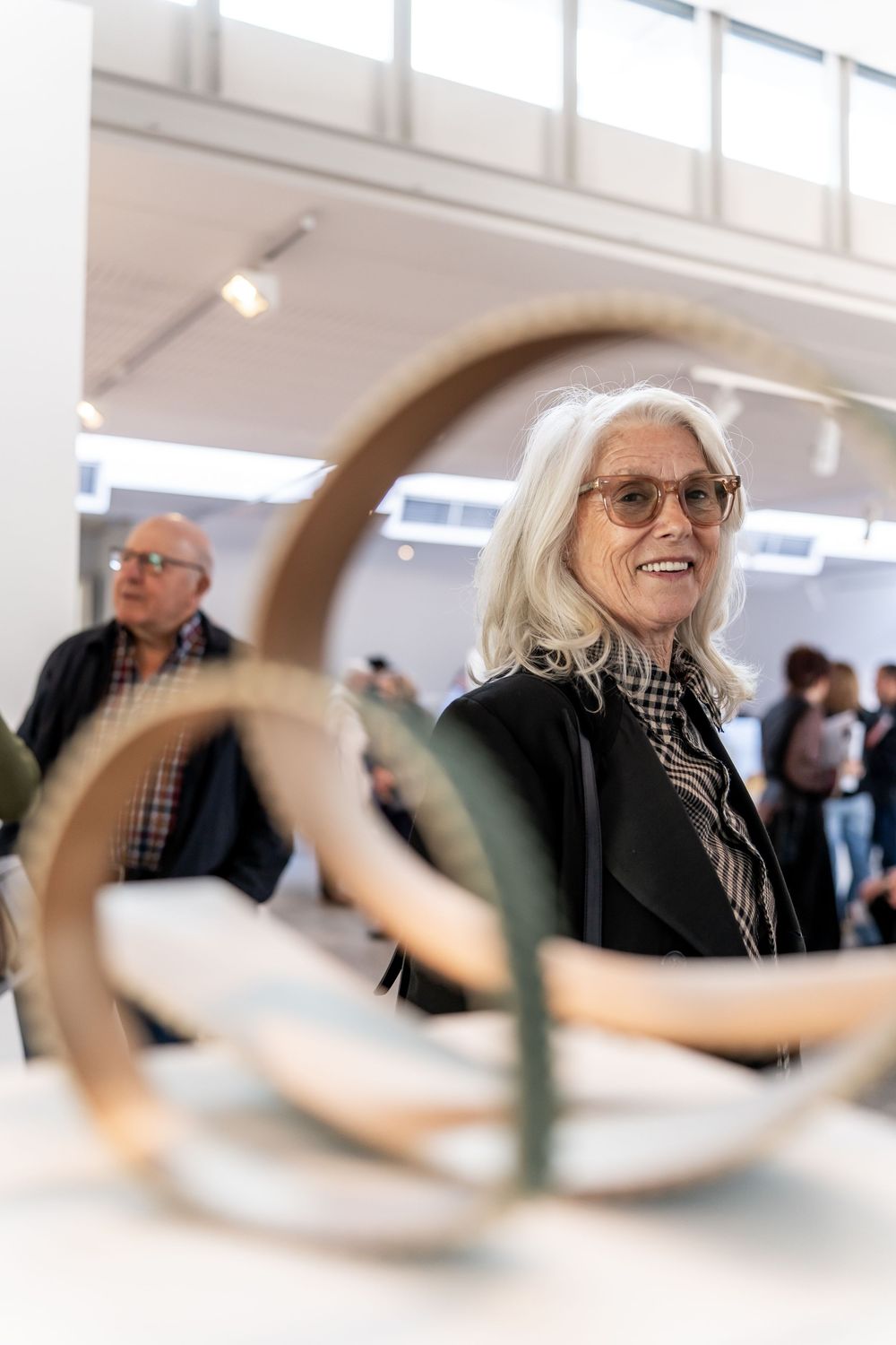 A series of four similar photos showing someone with white hair and glasses through a blurred foreground element.