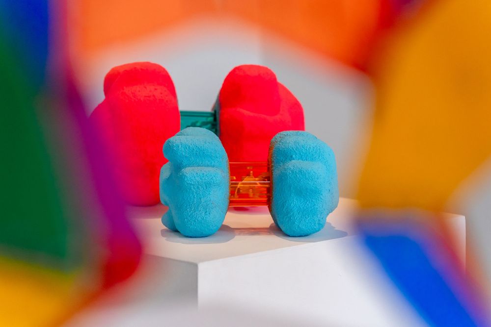Colorful macarons in vibrant red and turquoise blue arranged in a repeating pattern against a blurred background.