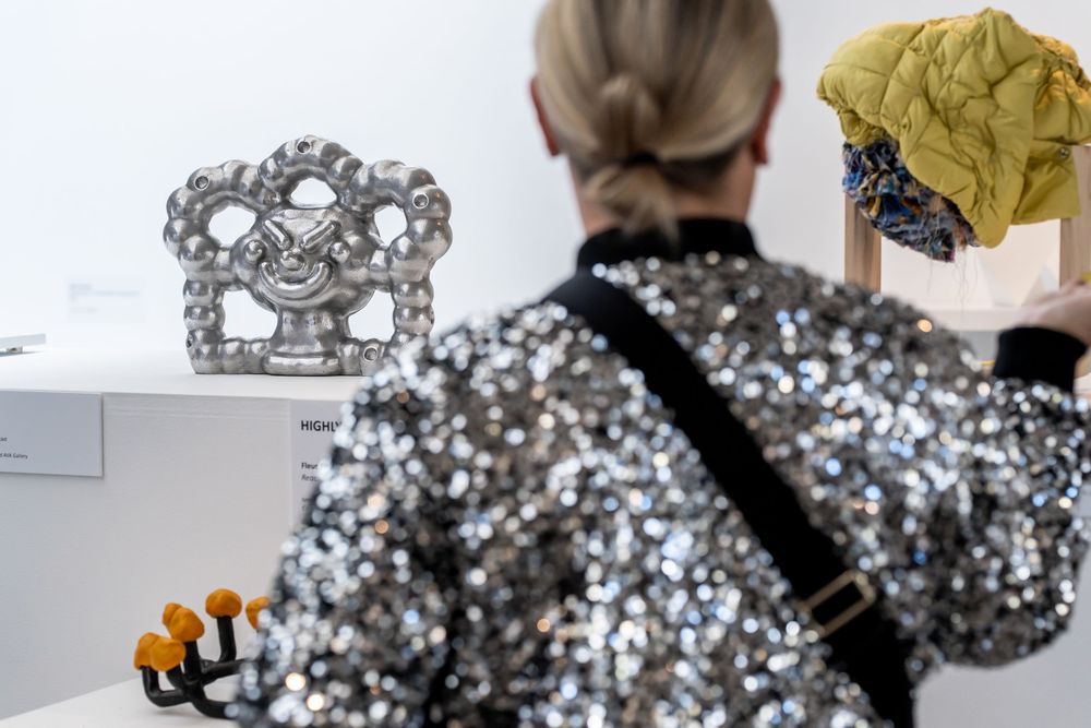 Shiny metallic spheres arranged in a sculptural form create an abstract art installation in a gallery space.