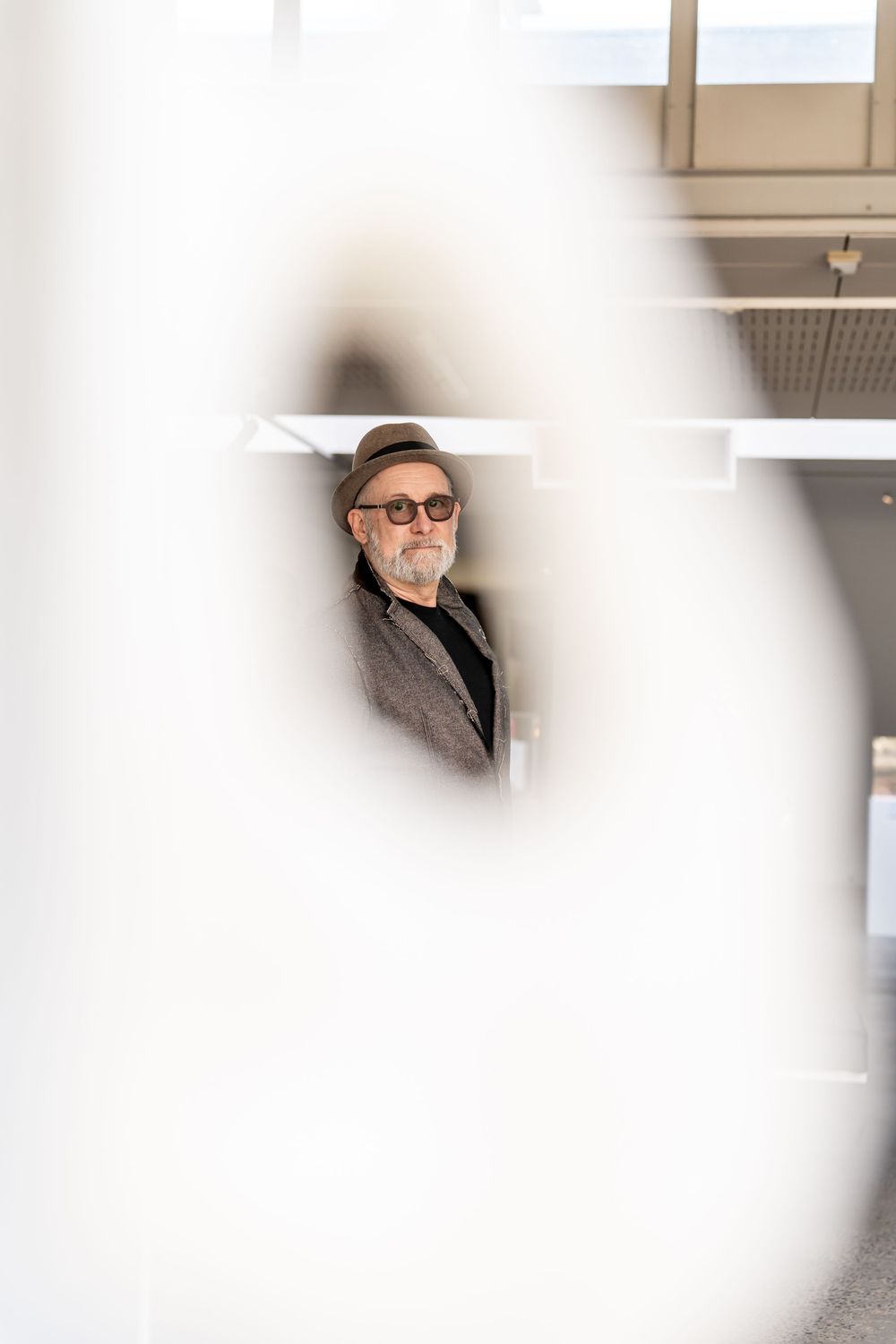 A person wearing sunglasses and a hat sits in what appears to be an indoor setting.