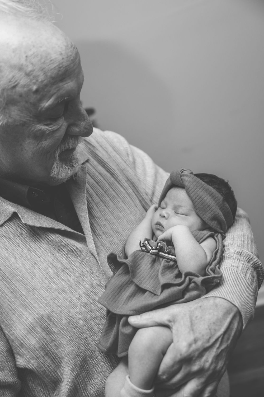 A tender black and white photo series showing a loving moment between a grandparent and sleeping baby.