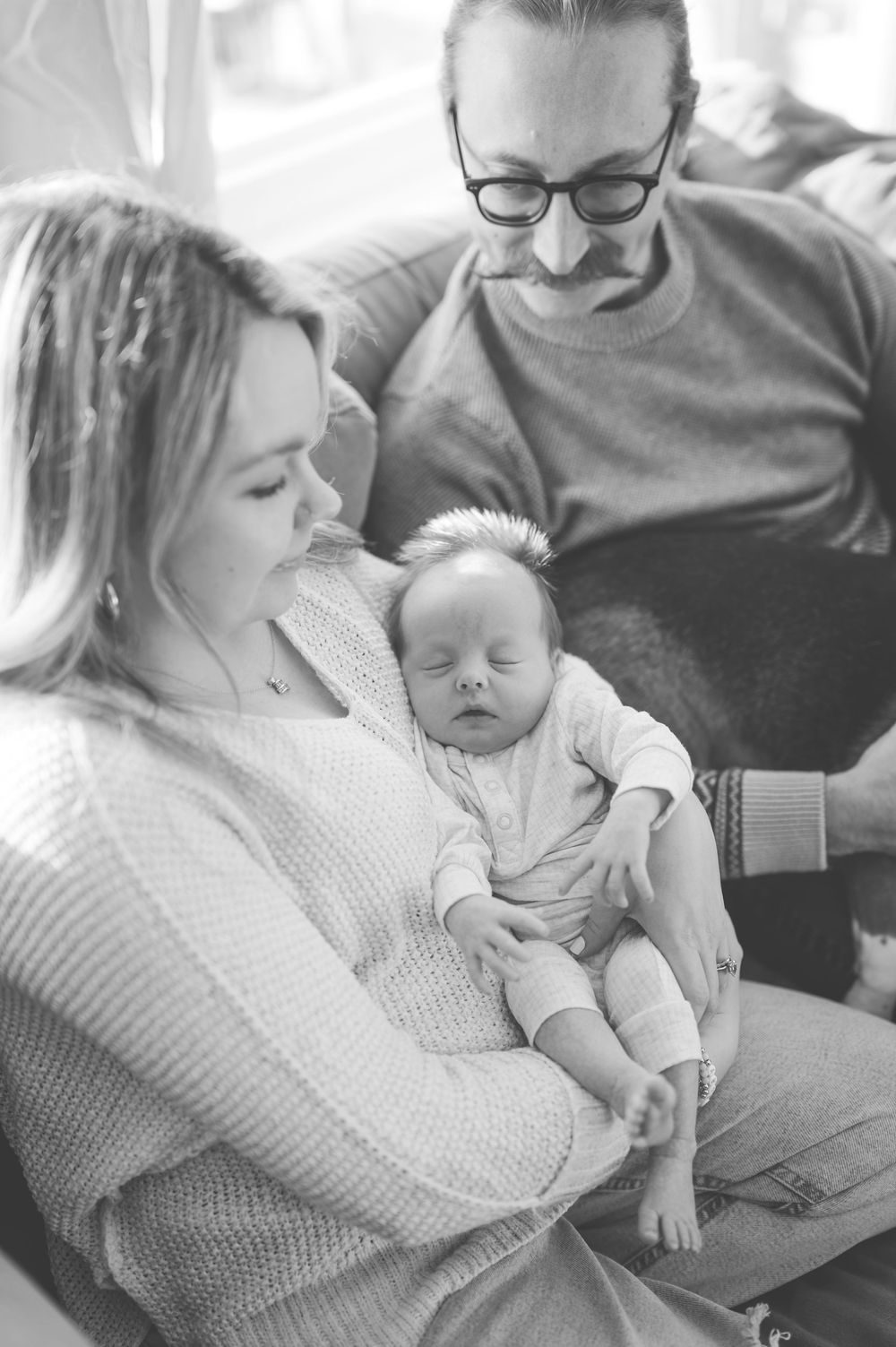 Black and white series of intimate family moments showing a baby being cradled and held in various tender poses.