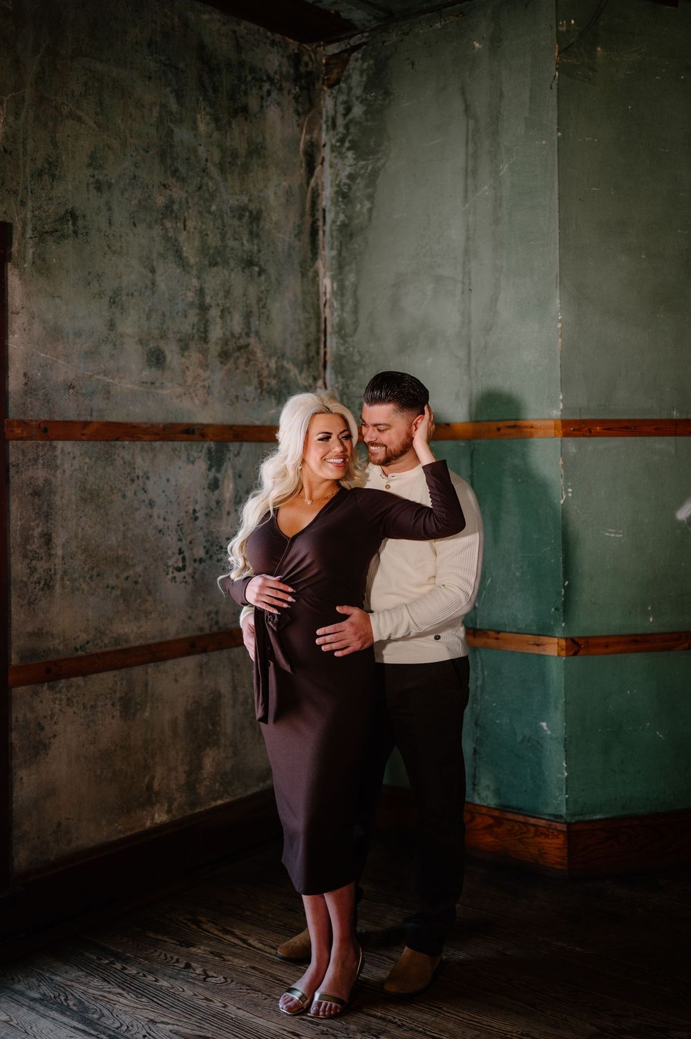 A couple shares an intimate dance moment in a dimly lit industrial space with green walls.