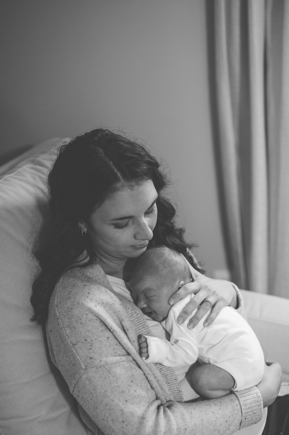 A tender moment captured in black and white as a parent lovingly embraces and comforts their sleeping baby.