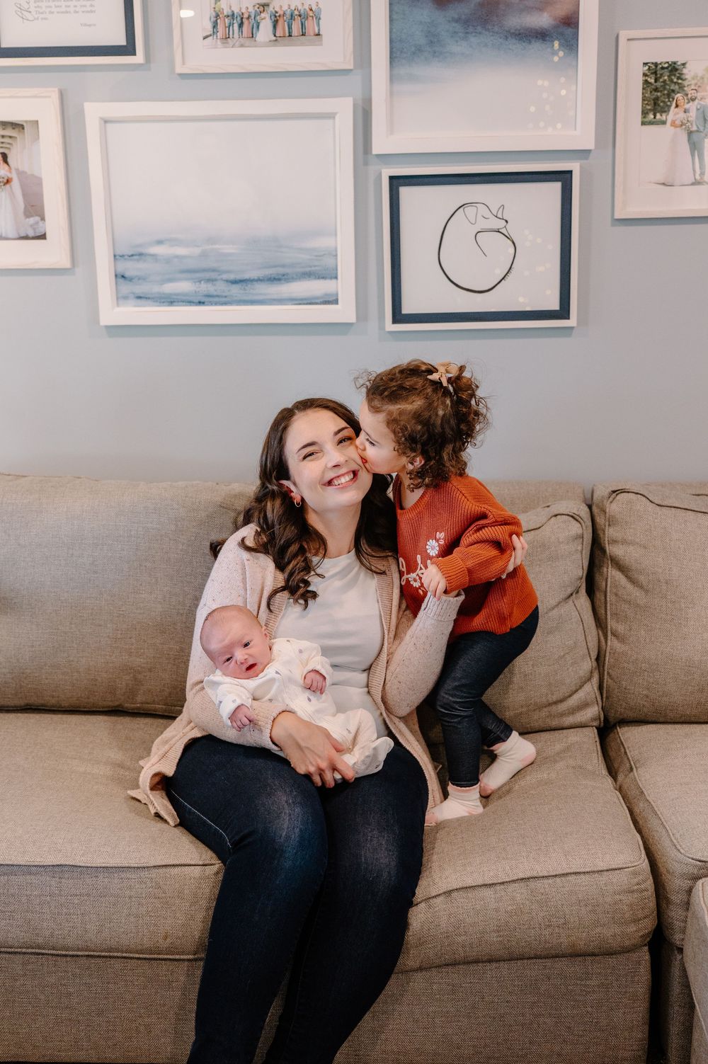 A series of four candid moments showing a mother and baby bonding on a gray couch with framed artwork on the wall.