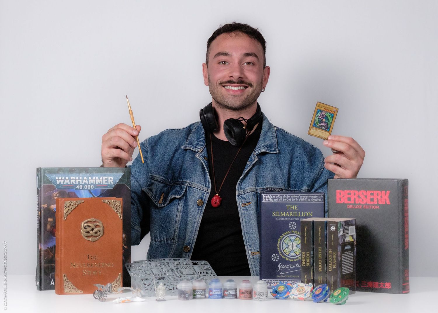 Someone displays gaming merchandise and collectibles including cards and figurines while holding up items at a white table.