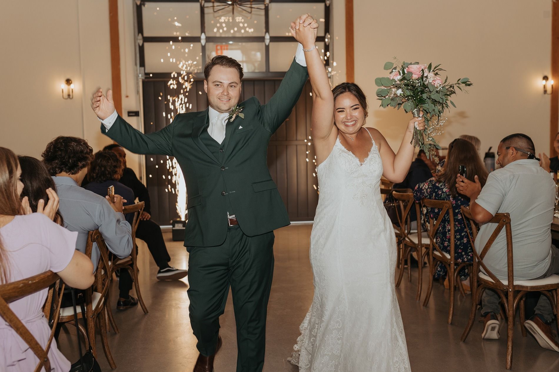 Newlyweds celebrate with raised arms while entering their wedding reception in an elegant indoor venue at Canopy Grove.