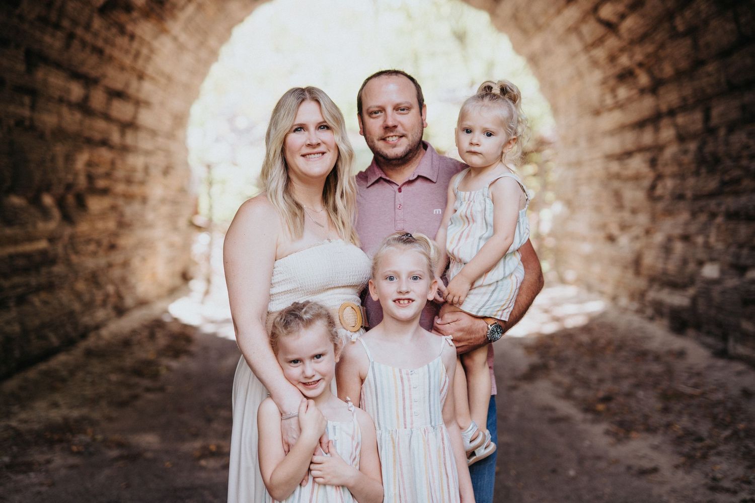 Family portrait session in rustic brick tunnel archway.