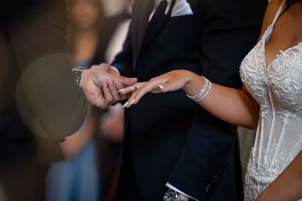 Groom places wedding ring on brides hand during ceremony.