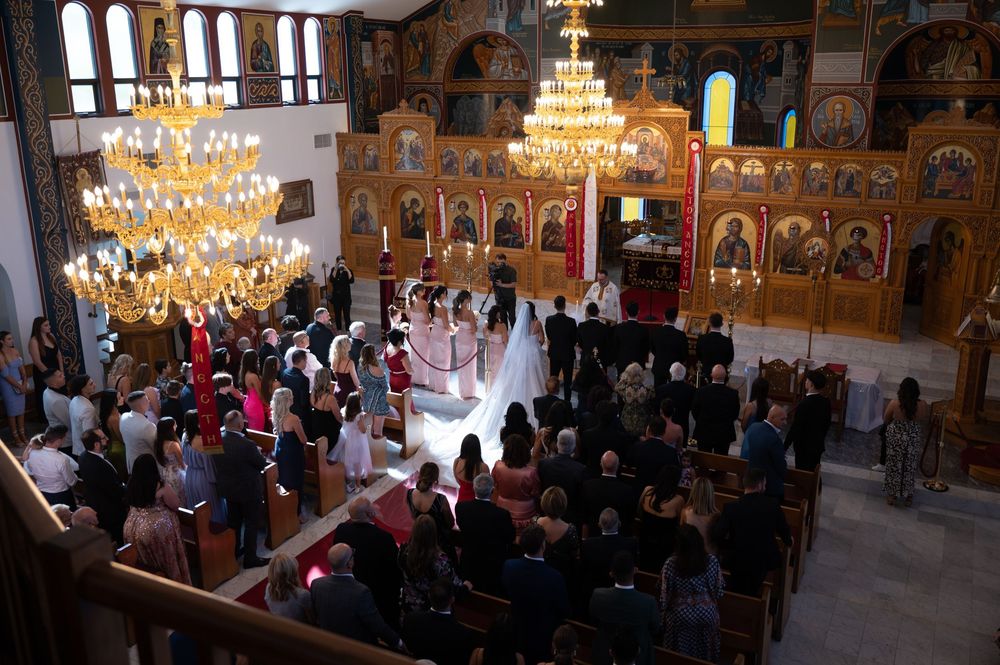 Overhead view of Greek Orthodox wedding ceremony with guests in church.