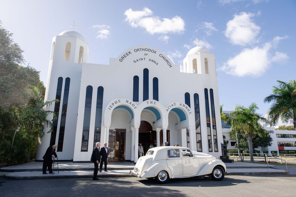 Classic white car parked outside Greek Orthodox Church Saint Andrew.